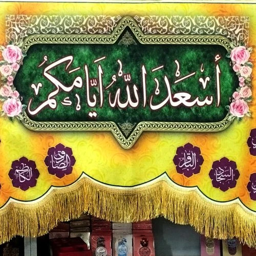 103292-کتیبه مخمل دالبری 140در300 طرح اسعدالله ایامکم با اسامی 14معصوم زمینه زرد و نارنجی
